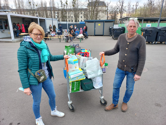 Zwei Personen schieben einen Wagen mit Lebensmitteln.