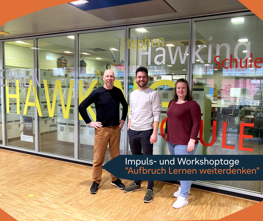 Drei Personen stehen vor einem Glasfenster mit der Aufschrift "Stephen Hawking Schule".