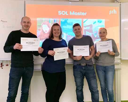 Vier Personen halten Zertifikate vor einem SOL Master-Banner.